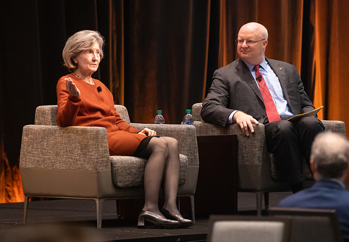 Two panelists speak on stage