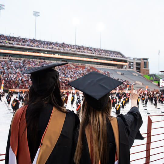 Back of two graduates wearing caps and gowns