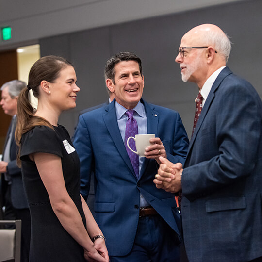 Three conference attendees network over coffee