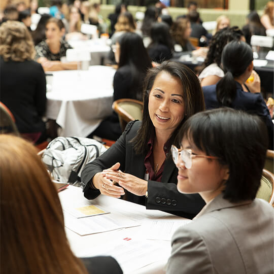 Conference attendees speak at a table together