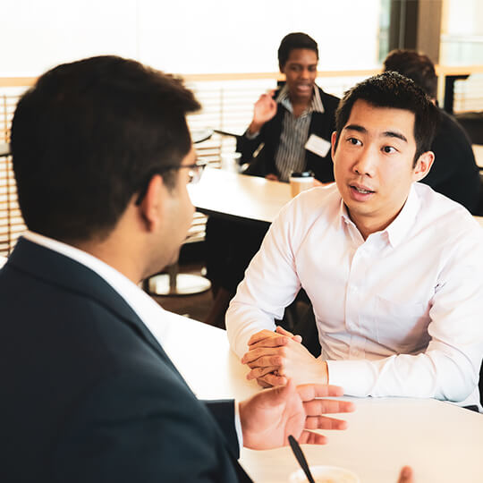 Two event attendees speak at a table