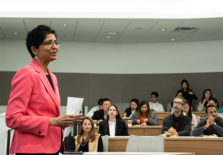 Meeta Kothare stands and speaks in front of a full class