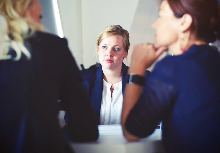 Person sits at a table across from two other people