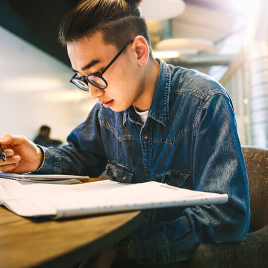 Person leaning over notebook taking notes