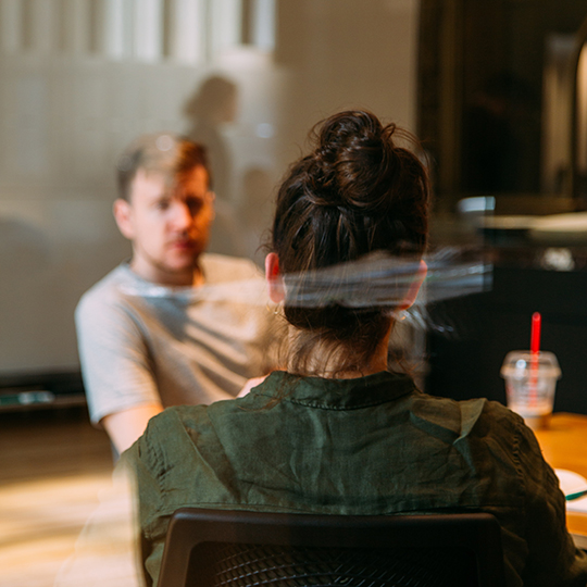 View of two people sitting at a conference table through a window