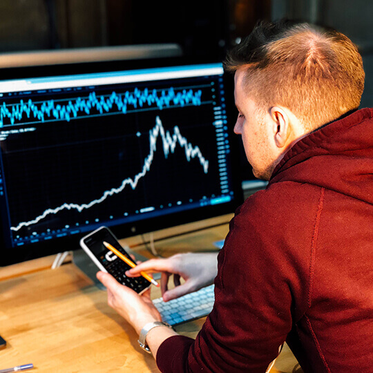 Back of person looking at graph on computer while holding phone