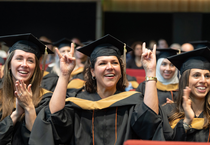 students smiling while in graduation cap and gown