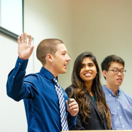 Four students speaking at front of healthcare class.