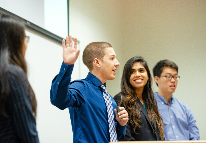 Four students speaking at front of healthcare class