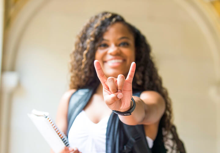 Smiling student gives hook em horns