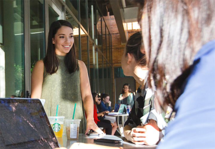 Smiling standing student talks to other seated students