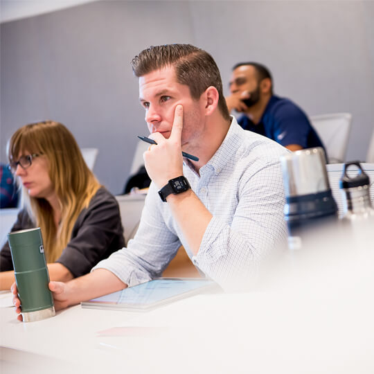 Three students listen in lecture hall