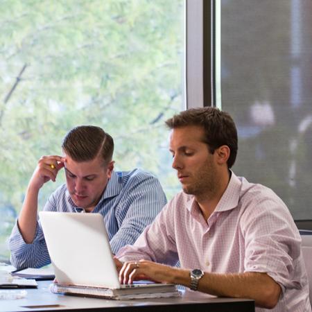 Two MBA students looking at a laptop together