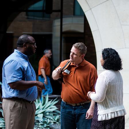 Three executive students stand and network together