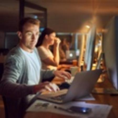 Two people working at night in an office with bright screens.