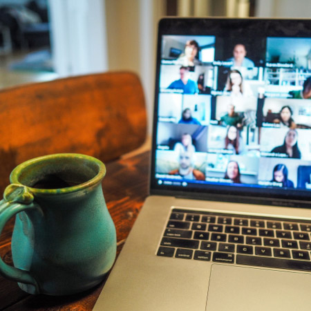 An open laptop with a green coffee mug next to it on a desk.