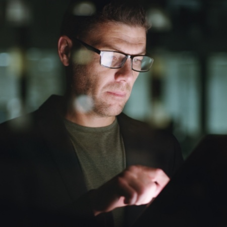 Man looking at computer screen in glass conference room.