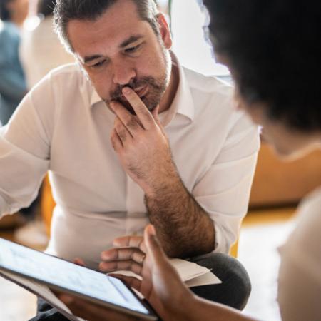 Man in white shirt looks at a tablet.