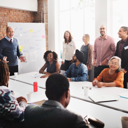 People sit at a white table talking at an office.